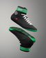 Black and green wrestling shoes with white laces on a gray background