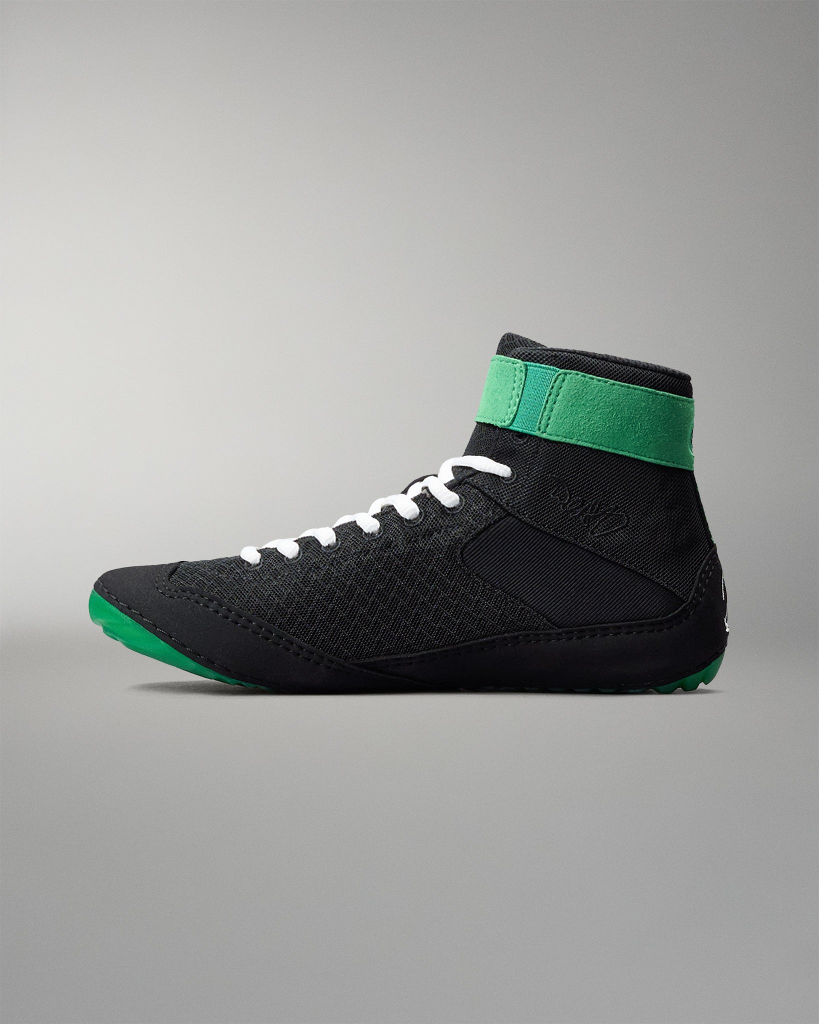 Black wrestling shoe with green accents on a gray background