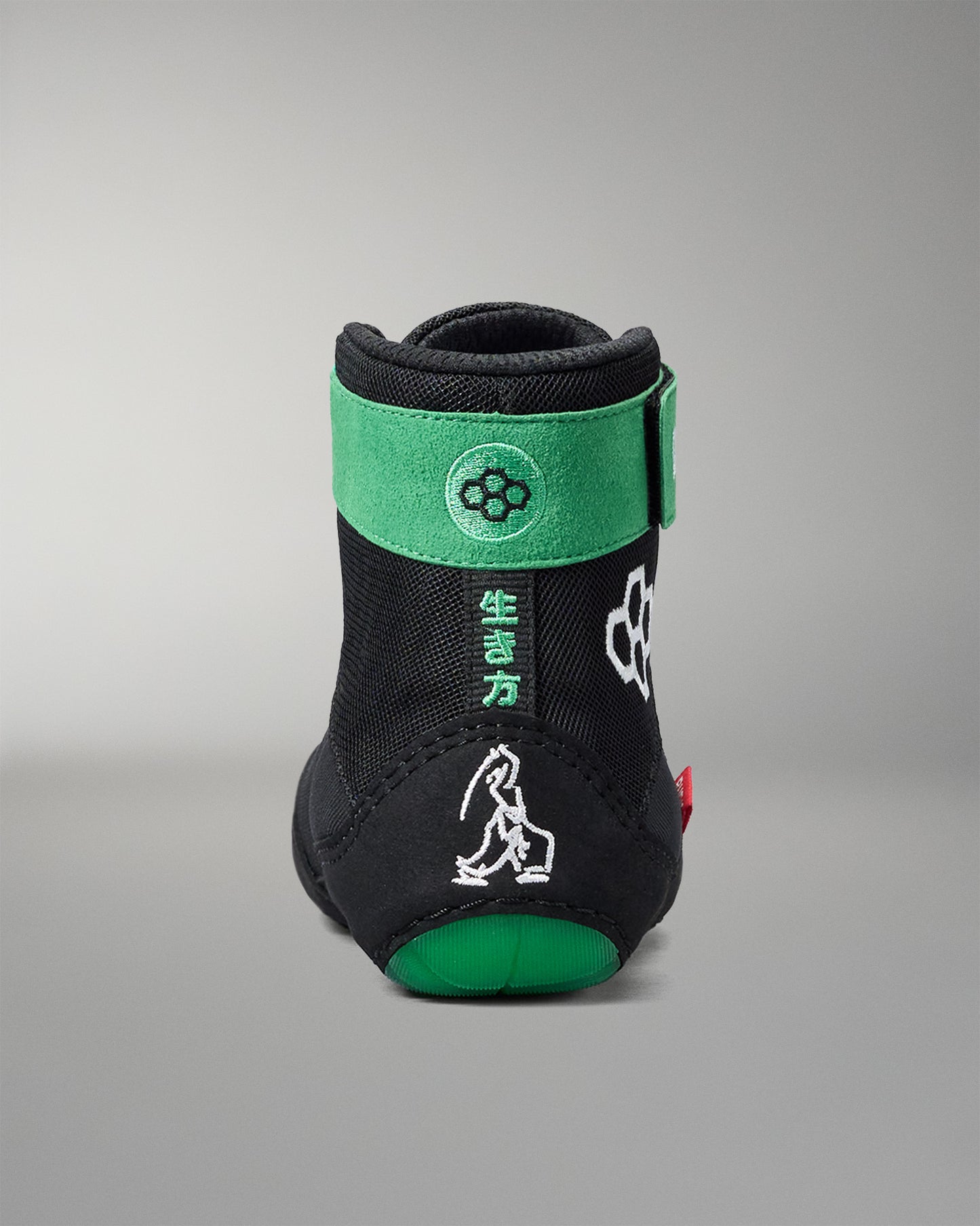 Black and green wrestling shoe with brand logo on a gray background