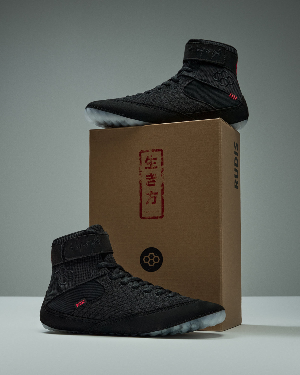 RUDIS Samurai Speed Adult Wrestling Shoes in Wabi-Sabi black with red accents, displayed on and beside a RUDIS shoebox with Japanese-inspired graphics.