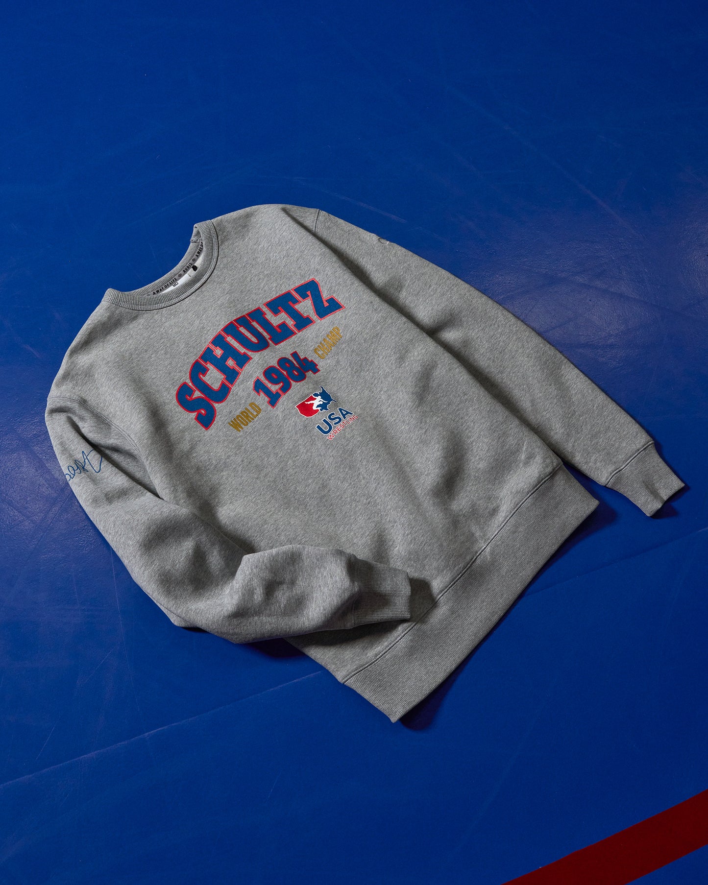 Gray sweatshirt with 'Schultz' branding on a blue background