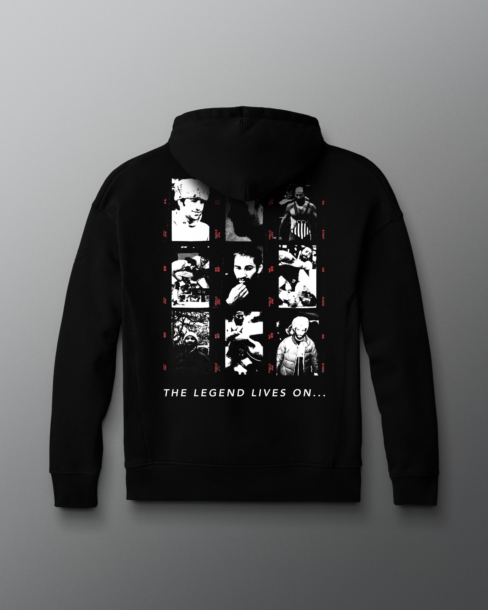Back view of a black hoodie featuring a grid of grayscale and red-accented photo portraits depicting various moments in a wrestler's life and career of Dave Schultz. Beneath the collage, bold white text reads: “THE LEGEND LIVES ON...”