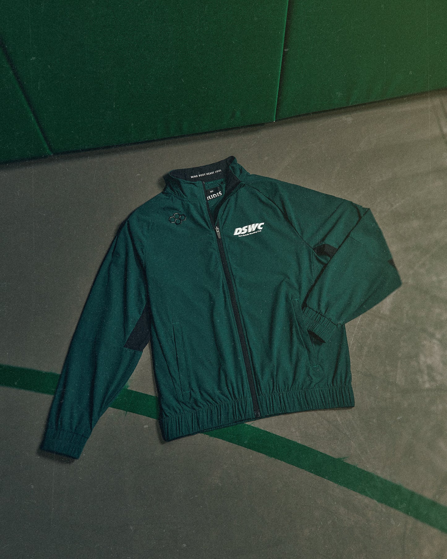 Green jacket with a logo on a green and gray floor
