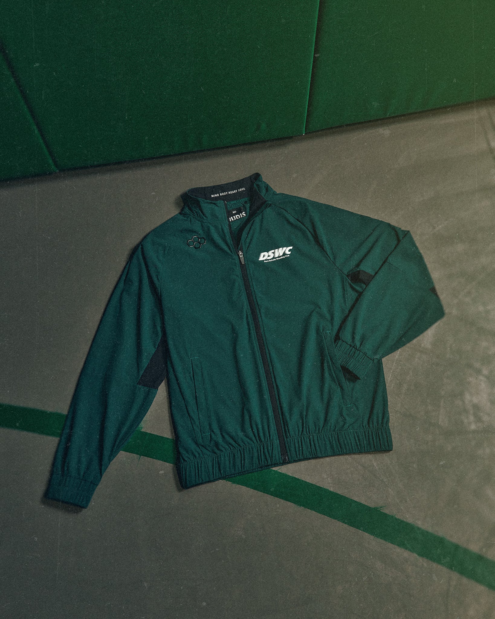 Green jacket with a logo on a green and gray floor