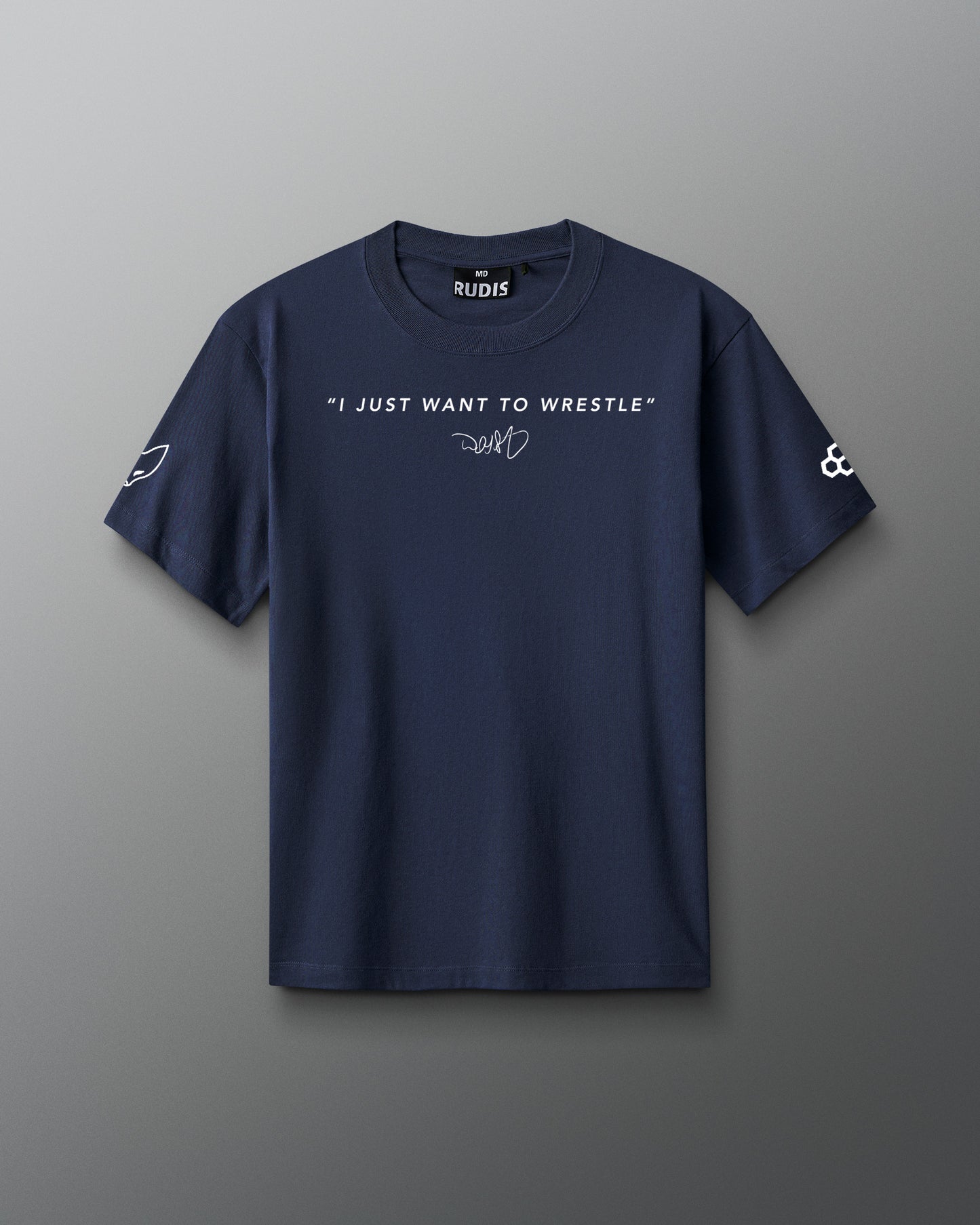 Front view of a navy RUDIS t-shirt featuring the quote “I JUST WANT TO WRESTLE” in white capital letters across the chest, with a signature-style graphic underneath. The left sleeve displays a stylized fox head icon, and the right sleeve features the RUDIS hex logo.
