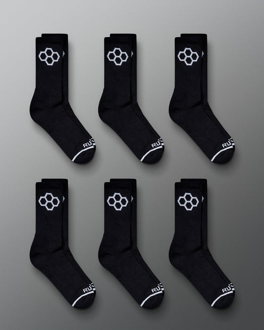 A display of six pairs of black athletic socks featuring a distinctive white hexagonal logo and stylish design details laid out on a gray background