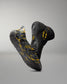 RUDIS black and yellow wrestling shoe covers shown with a black Batman wrestling shoe, highlighting the marbled protective outsole design.