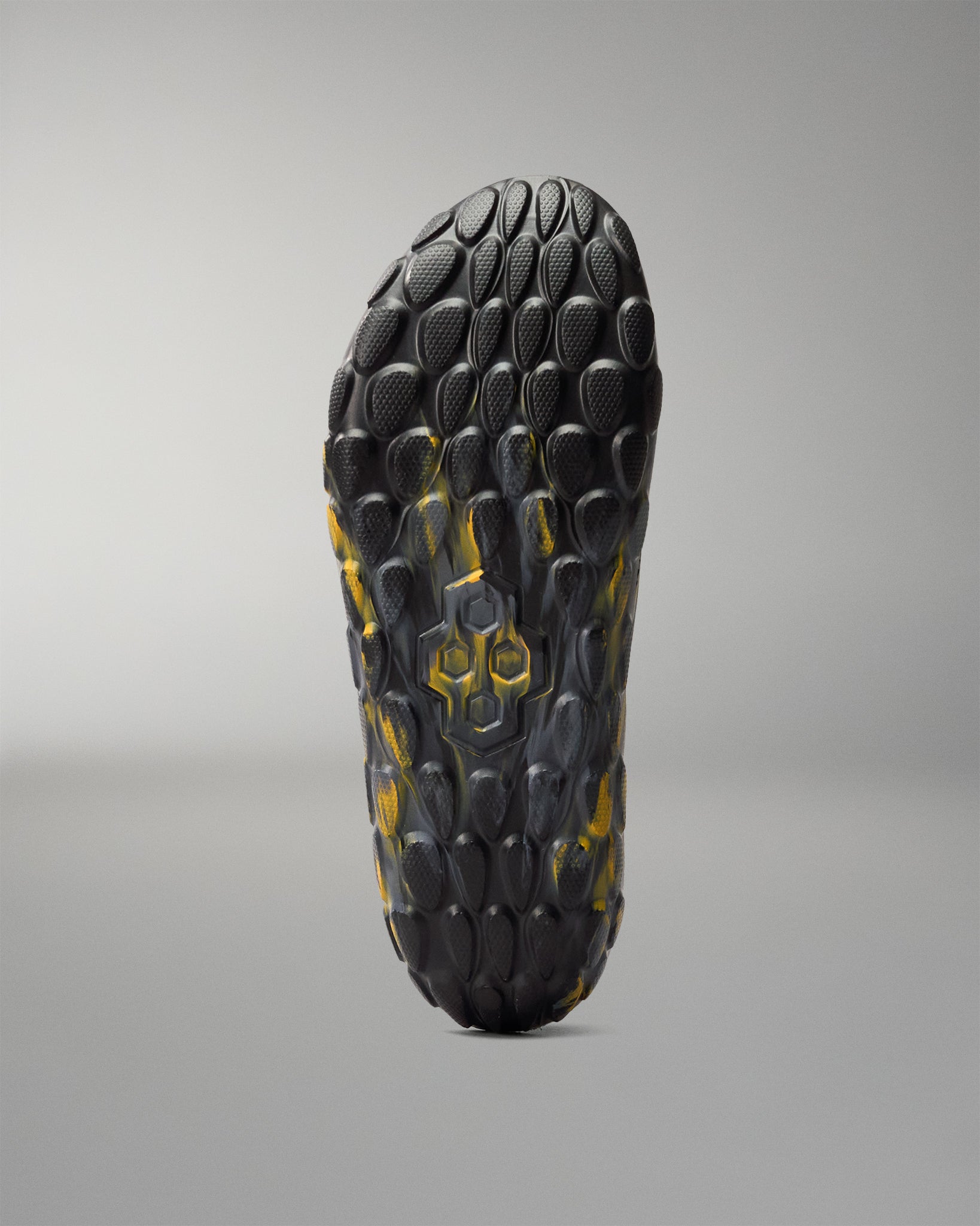 Bottom view of RUDIS black and yellow wrestling shoe cover showing the textured traction pattern and RUDIS hex logo.