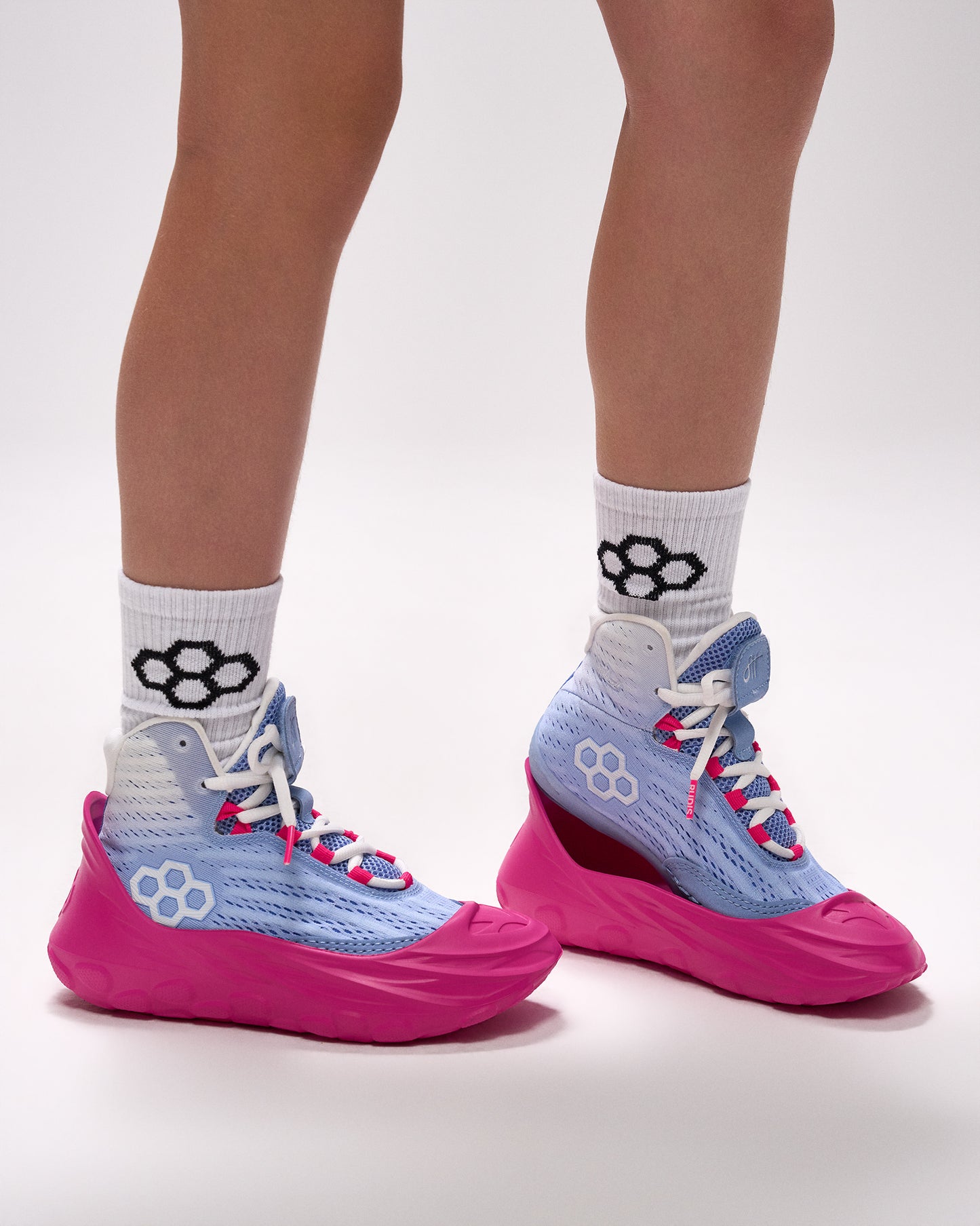 Athlete wearing RUDIS pink sole covers over blue wrestling shoes with lightweight slip-on protection design