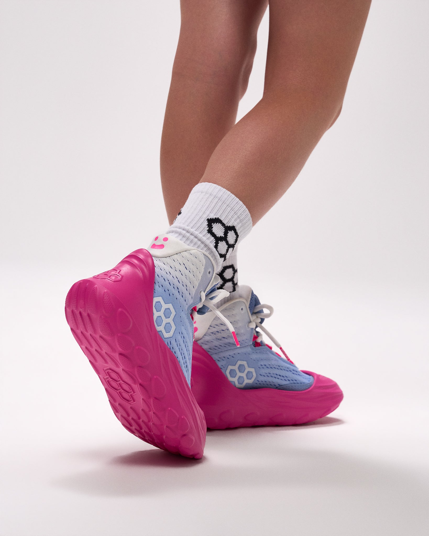 Pink and blue wrestling shoes with white socks featuring a black sock brand logo on a light gray background.