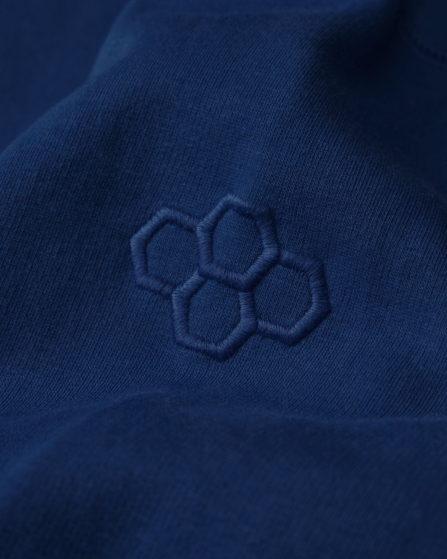 Close-up of a blue fabric with an embroidered hexagonal pattern