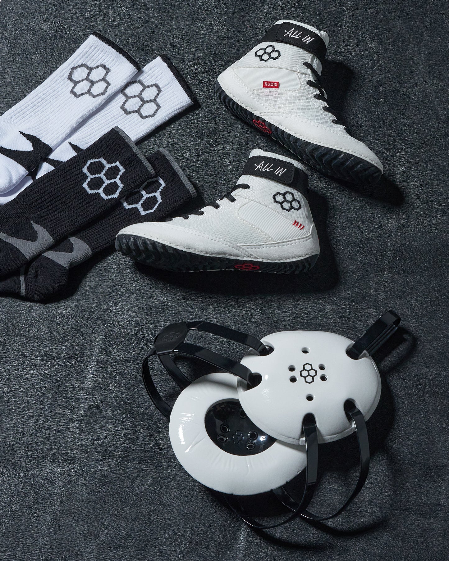 White wrestling with black and red accents, accompanied by matching socks and a white headgear on a dark surface.