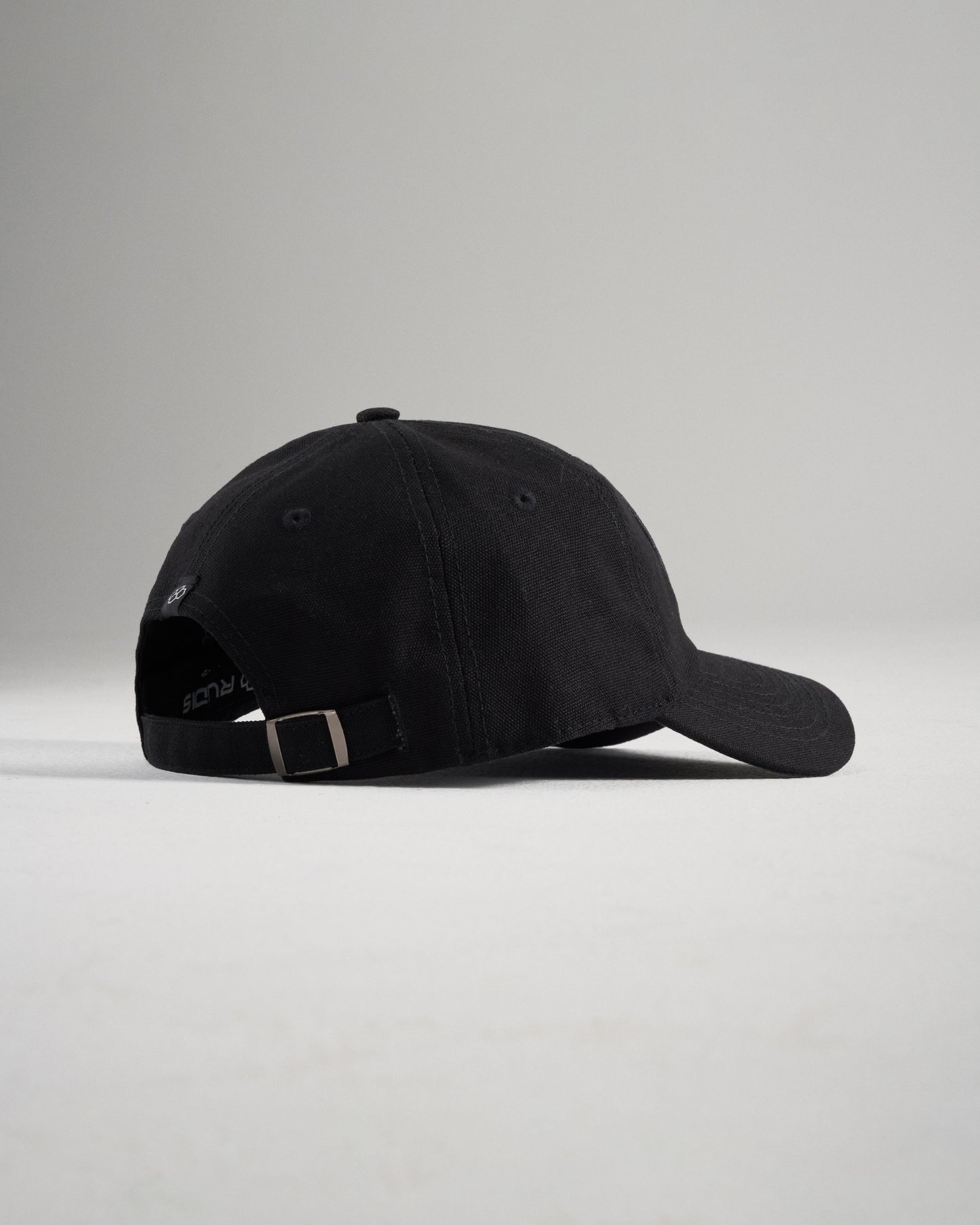 A simple black baseball cap viewed from the side showcasing its curved brim and adjustable strap at the back
