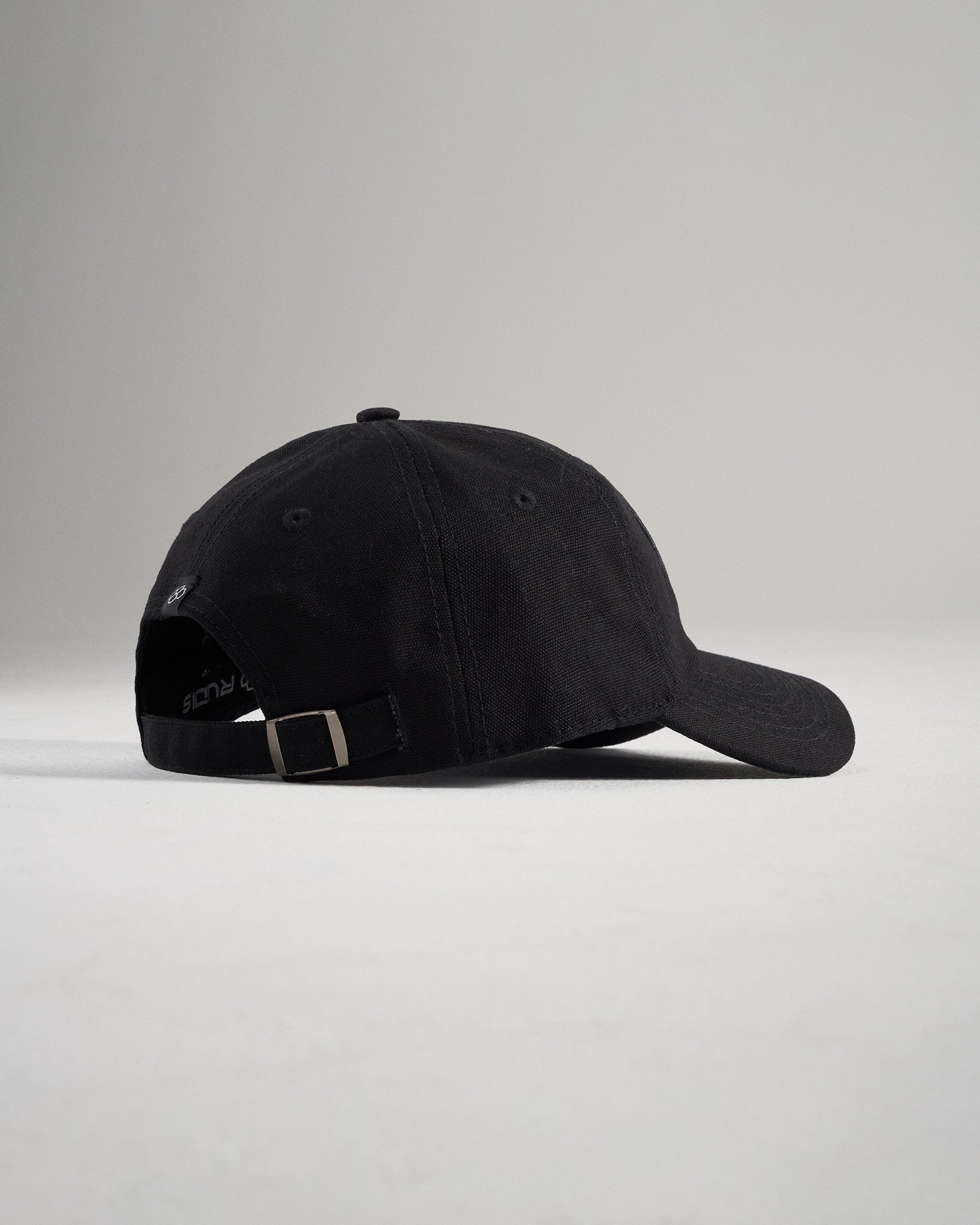A simple black baseball cap viewed from the side showcasing its curved brim and adjustable strap at the back