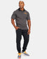 A fitness enthusiast poses in a sleek black polo shirt and black joggers complemented by colorful running shoes exuding a sporty and stylish aesthetic