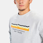 A close-up portrait of a young man wearing a light gray sweatshirt featuring a colorful graphic print of Sports Illustrated