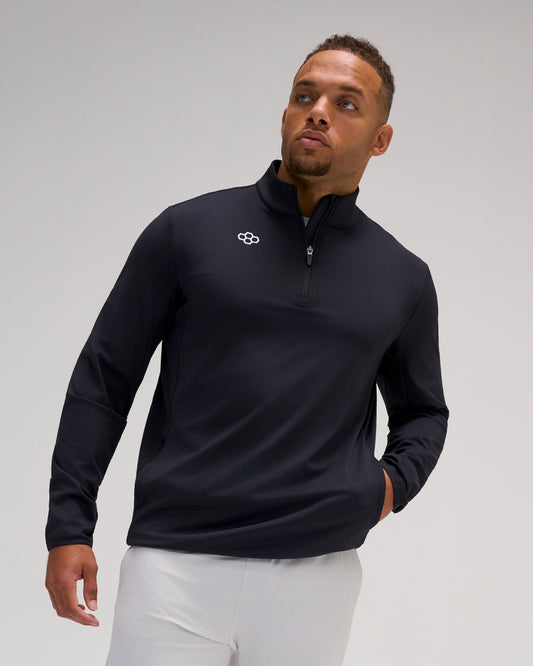 Model wearing the black RUDIS Victory 1/4 Zip performance pullover with quarter-zip collar, white RUDIS mark, and side pockets.
