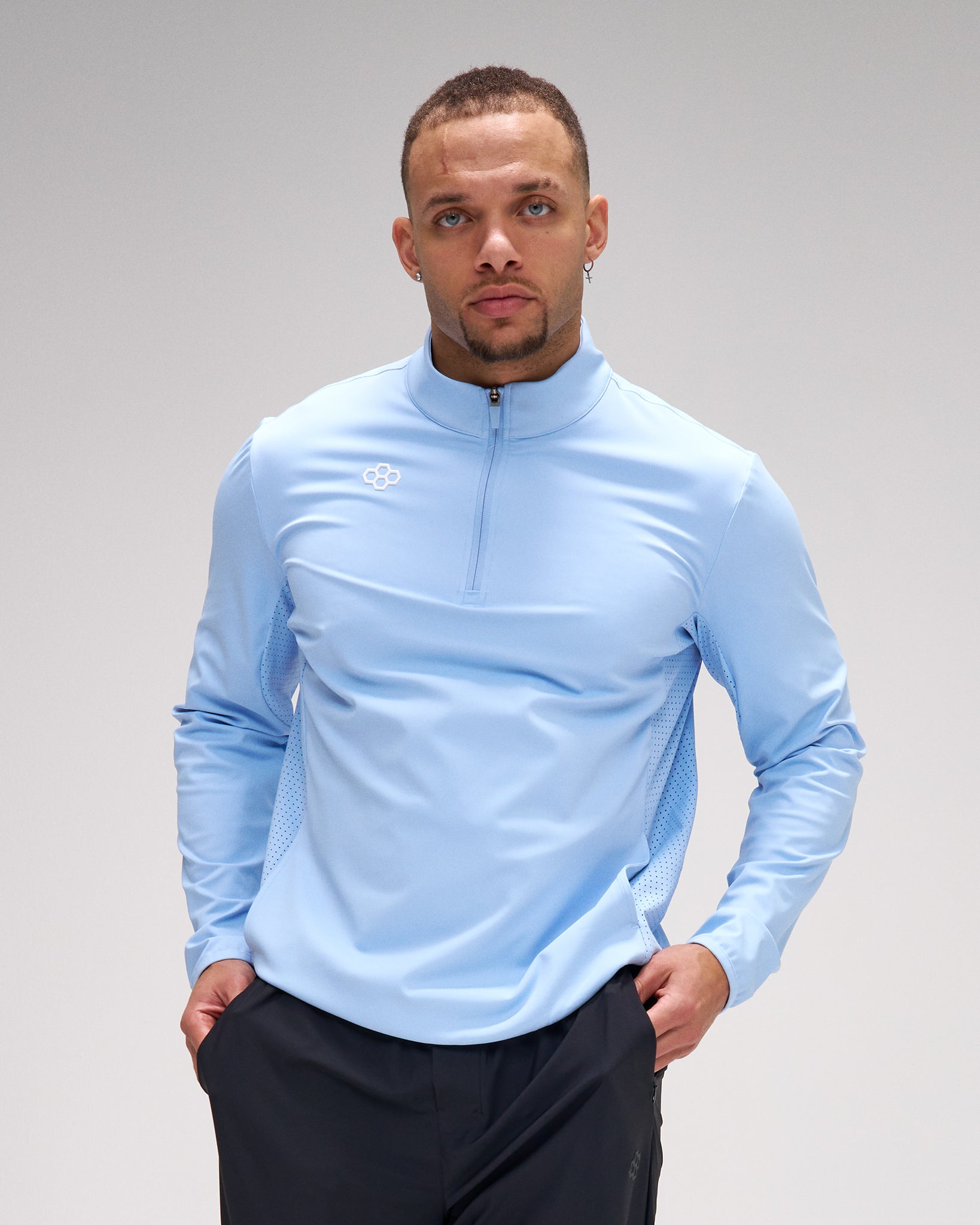 Man wearing a light blue long-sleeve athletic shirt with a brand logo on a gray background