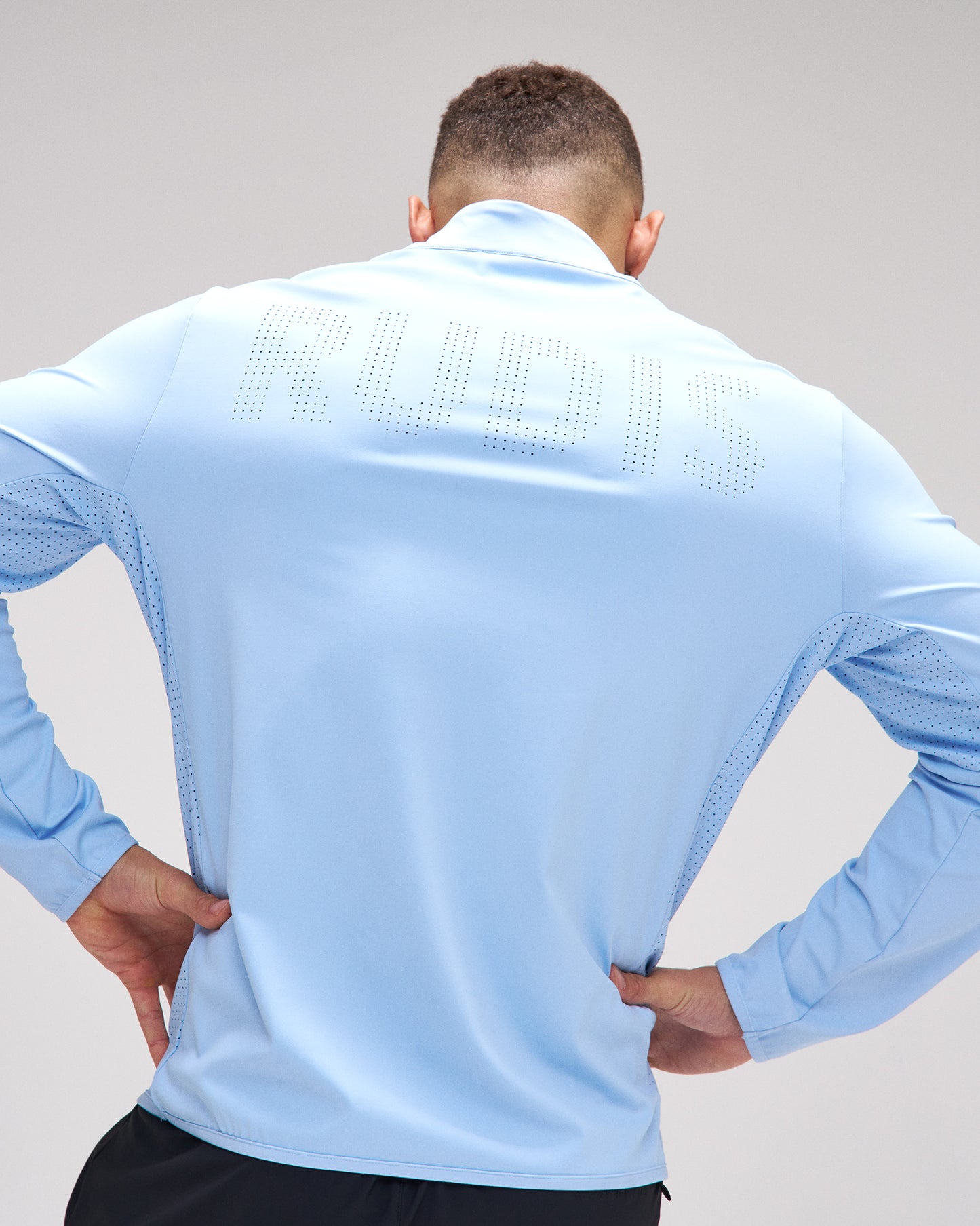 Person wearing a light blue athletic jacket on a plain background