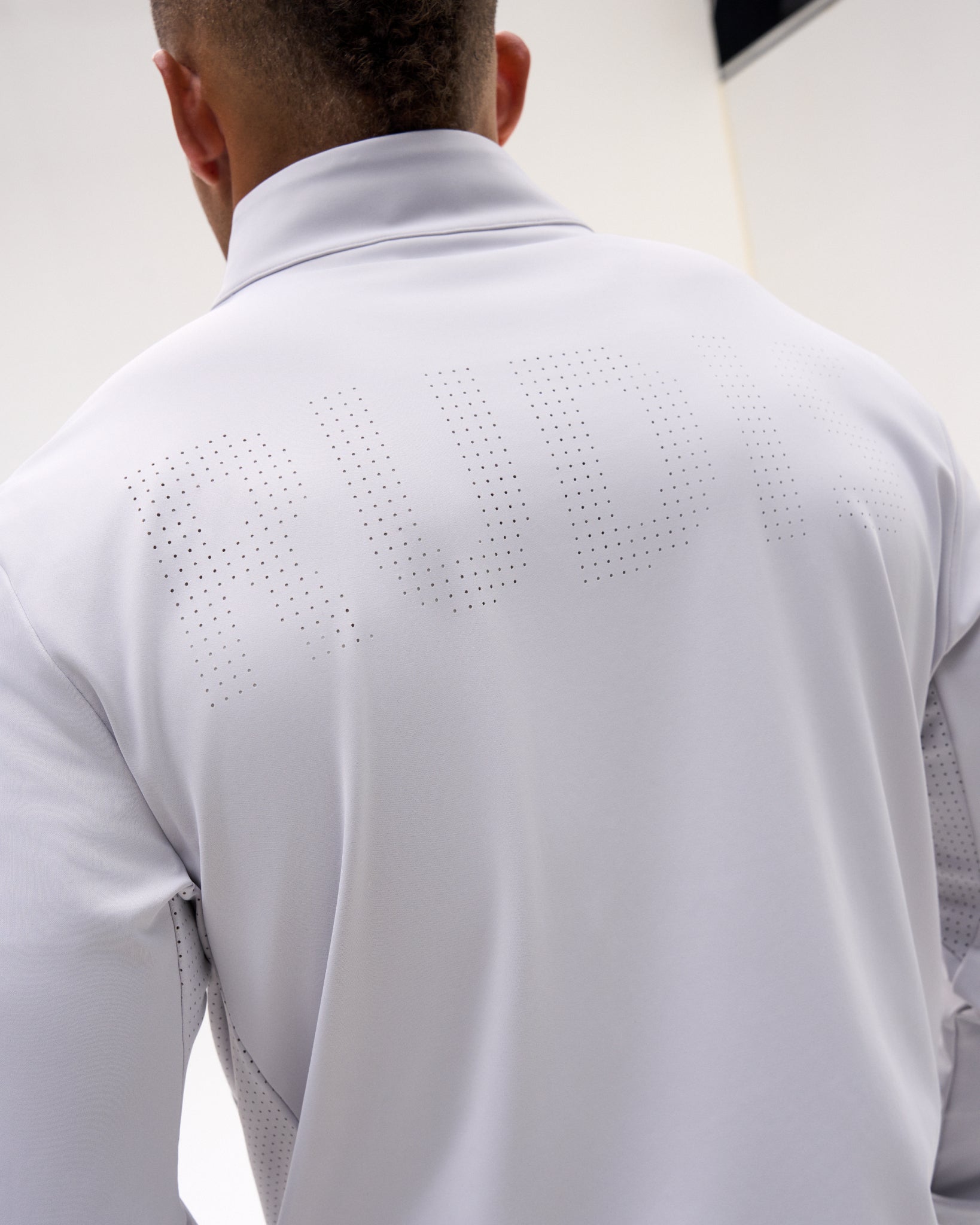 Back detail of the Lunar RUDIS Victory 1/4 Zip featuring perforated RUDIS branding across the upper back and ventilated side panels.