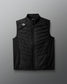 Black quilted vest with a brand logo on a gray background