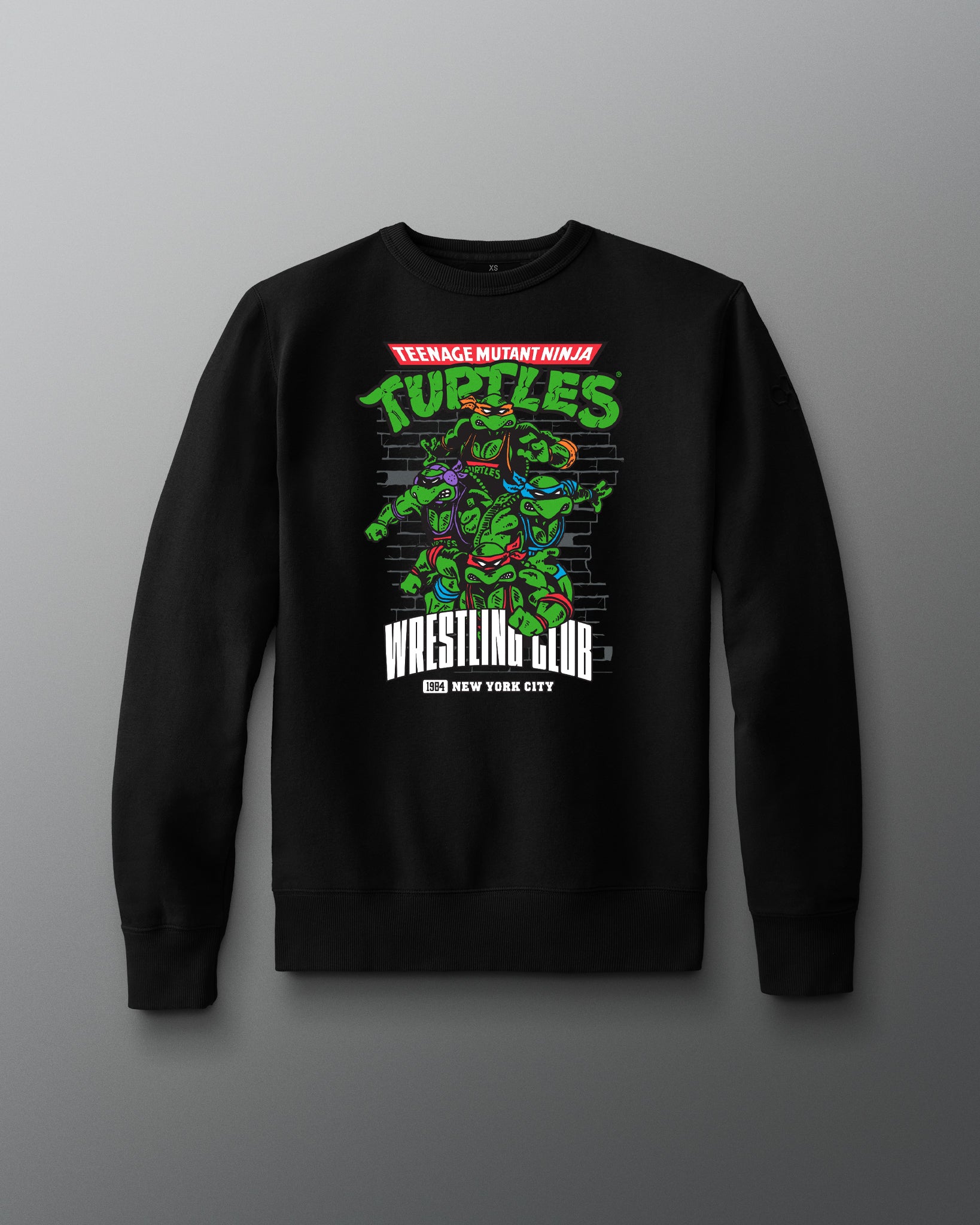 Black sweatshirt with Teenage Mutant Ninja Turtles graphic on a gray background