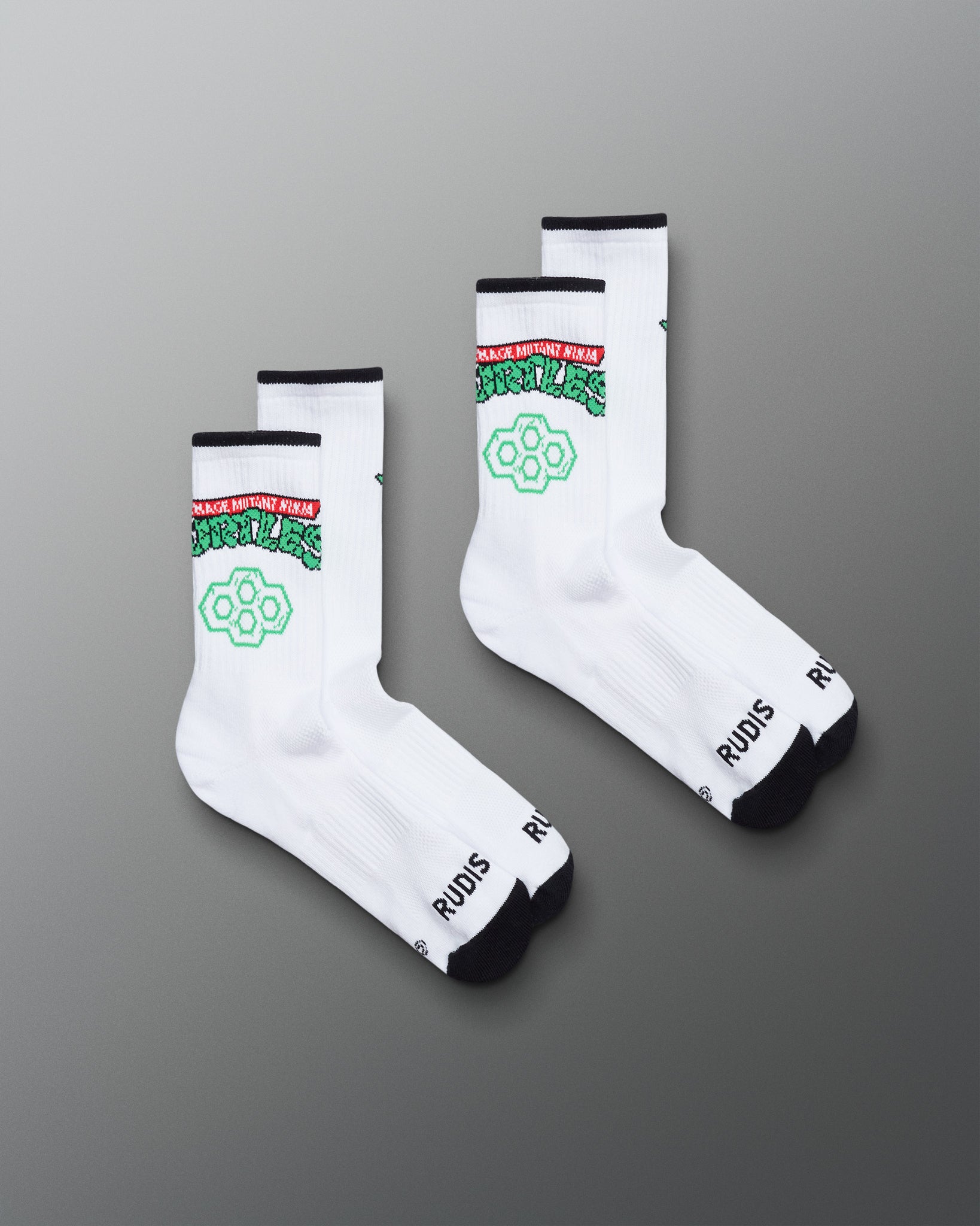 White socks with green and black text on a gray background. TMNT. Teenage Mutant Ninja Turtles