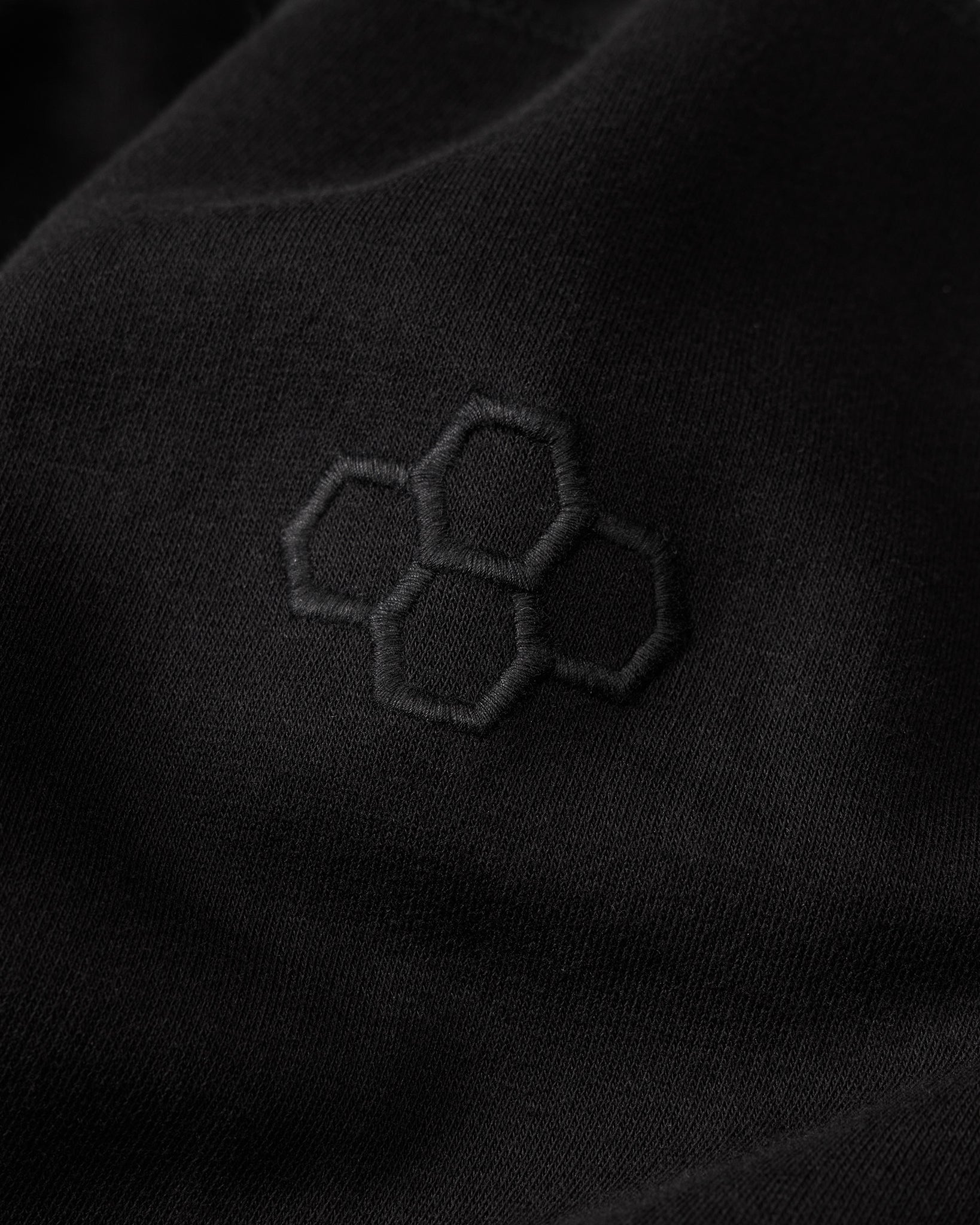 Close-up of a black fabric with an embroidered hexagonal pattern.