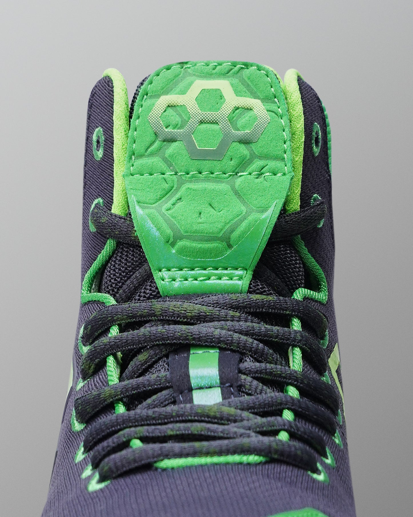 Close-up of a Wrestling shoe with green and black design on a gray background