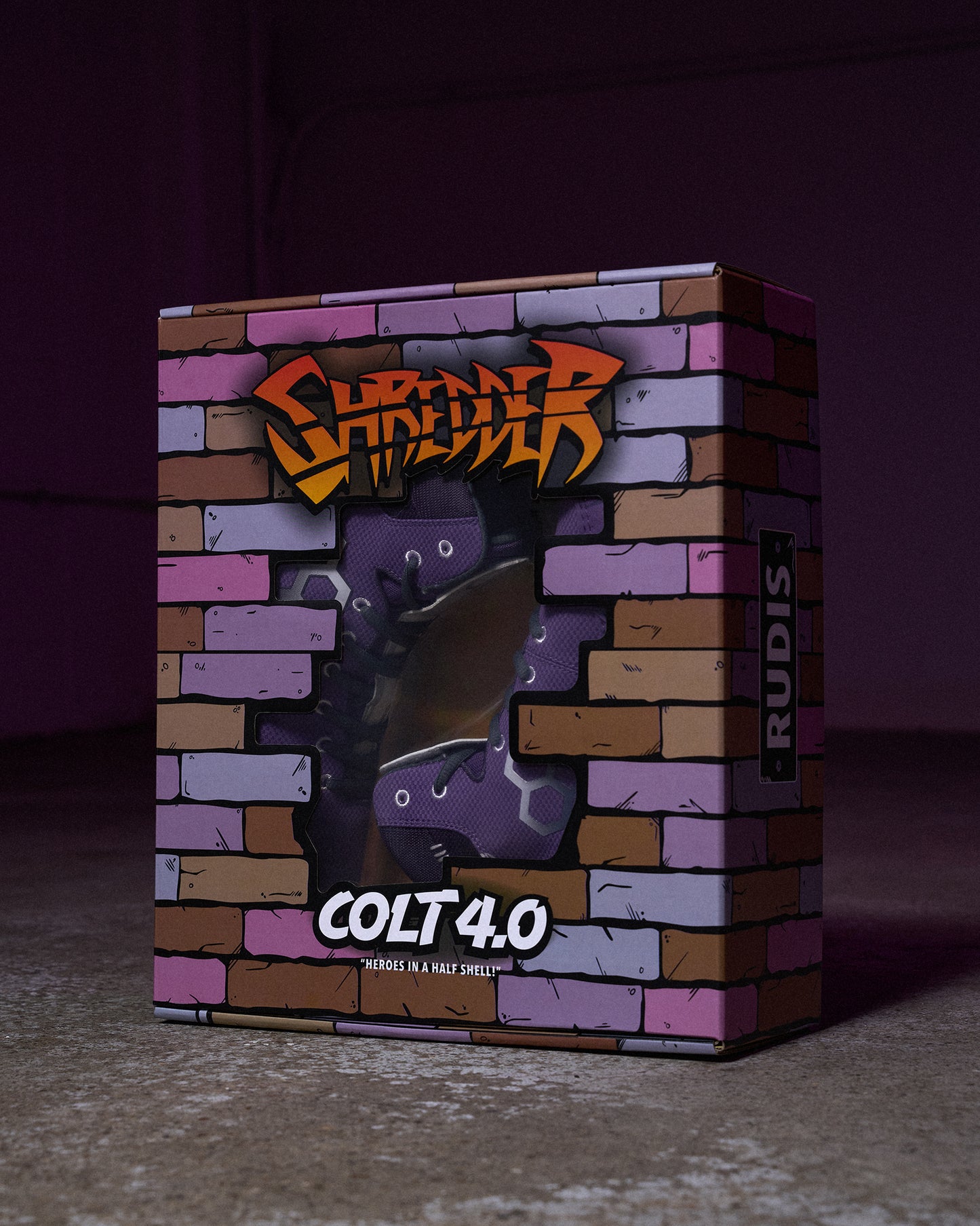 RUDIS Colt 4.0 Shredder wrestling shoes displayed inside a custom Teenage Mutant Ninja Turtles-inspired collector box featuring a brick wall design, Shredder artwork, and a clear display window.
