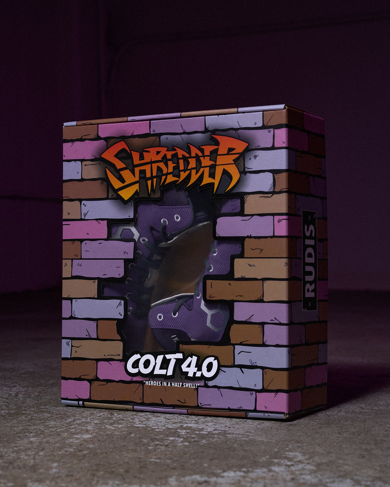 RUDIS Colt 4.0 Shredder wrestling shoes displayed inside a custom Teenage Mutant Ninja Turtles-inspired collector box featuring a brick wall design, Shredder artwork, and a clear display window.
