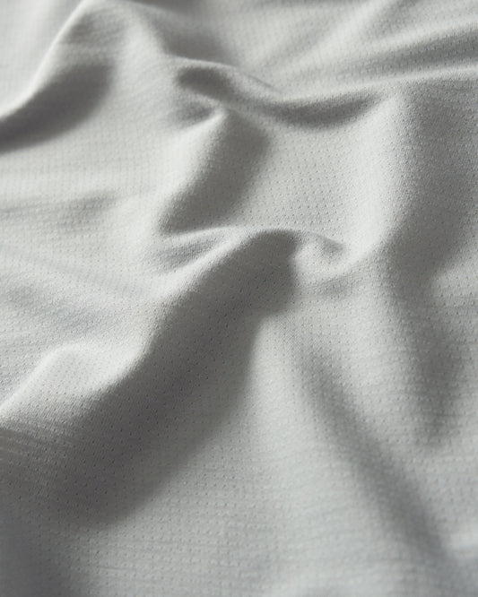 Light gray textured fabric with a dotted pattern shows subtle folds and a soft surface suitable for clothing or upholstery.