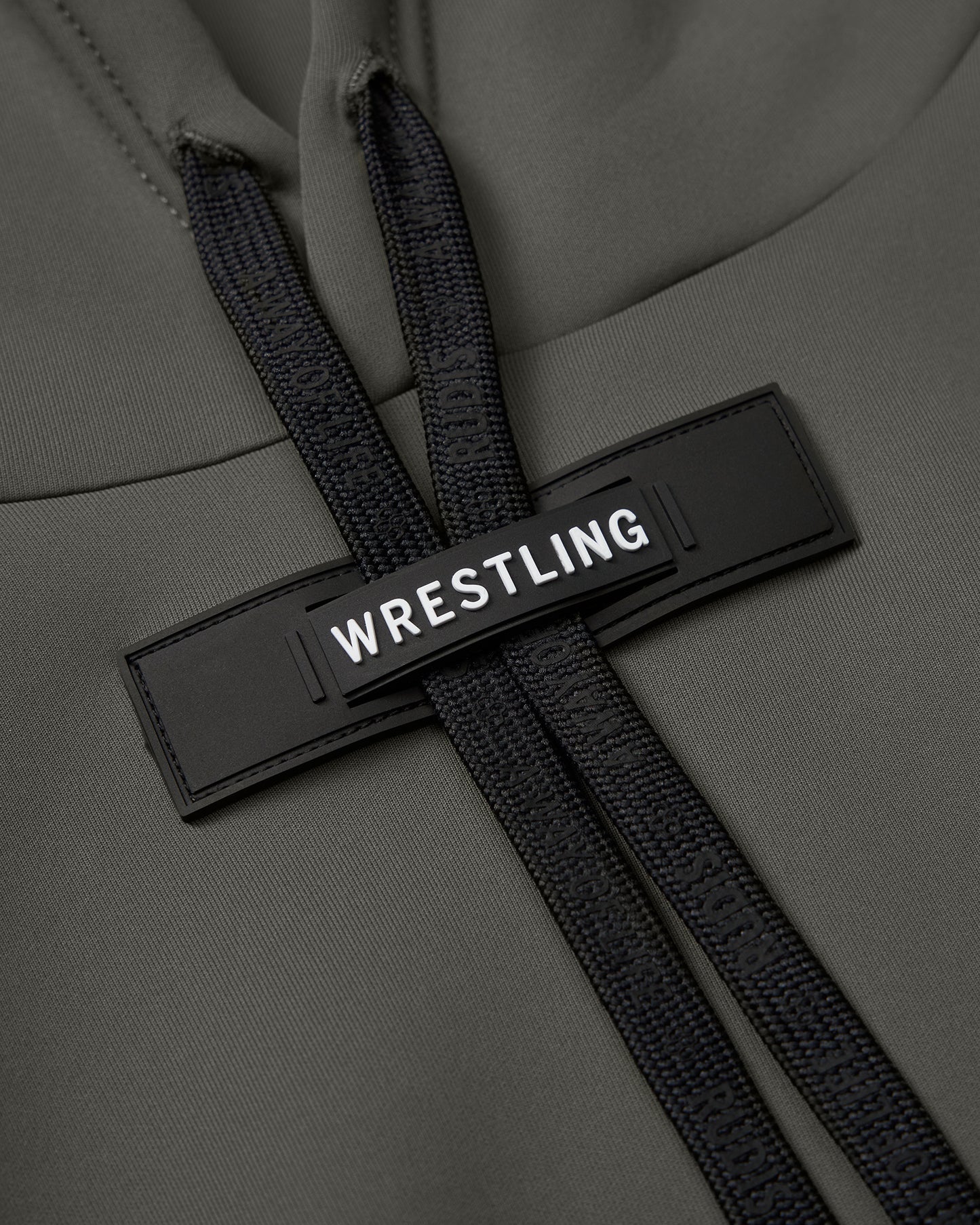 Close-up of a green hoodie with a black 'WRESTLING' tag and textured black drawstrings, showcasing a stylish and functional design.