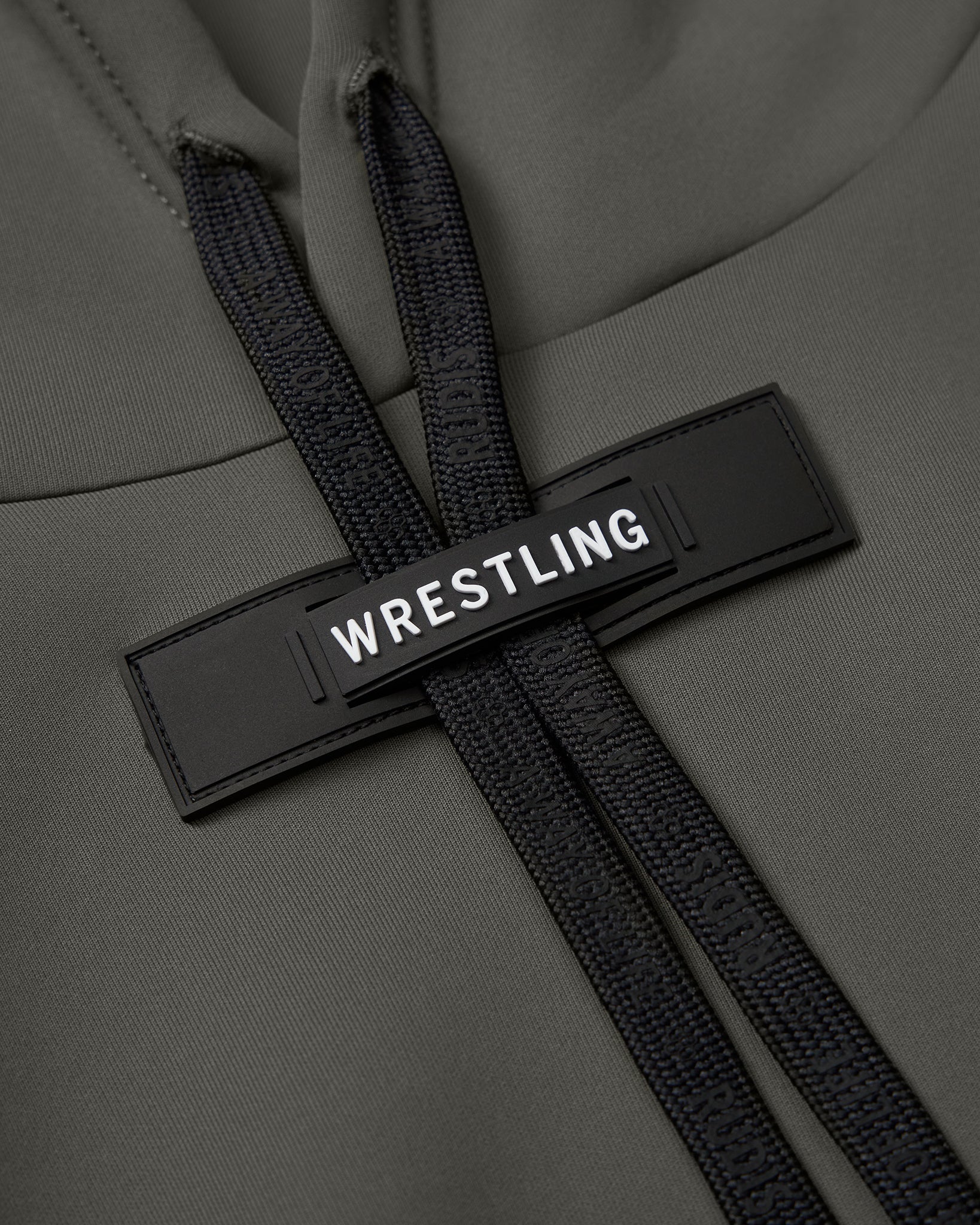 Close-up of a green hoodie with a black 'WRESTLING' tag and textured black drawstrings, showcasing a stylish and functional design.