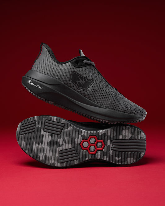 Black athletic shoe with a red logo on a red background