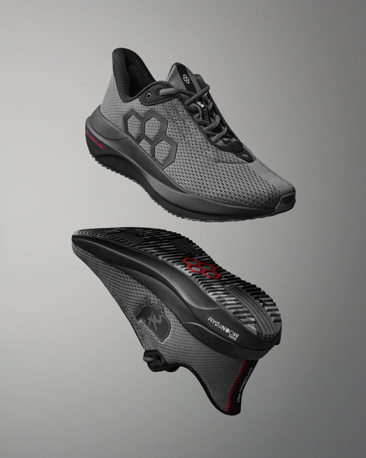 Gray athletic shoe with black sole on a gray background