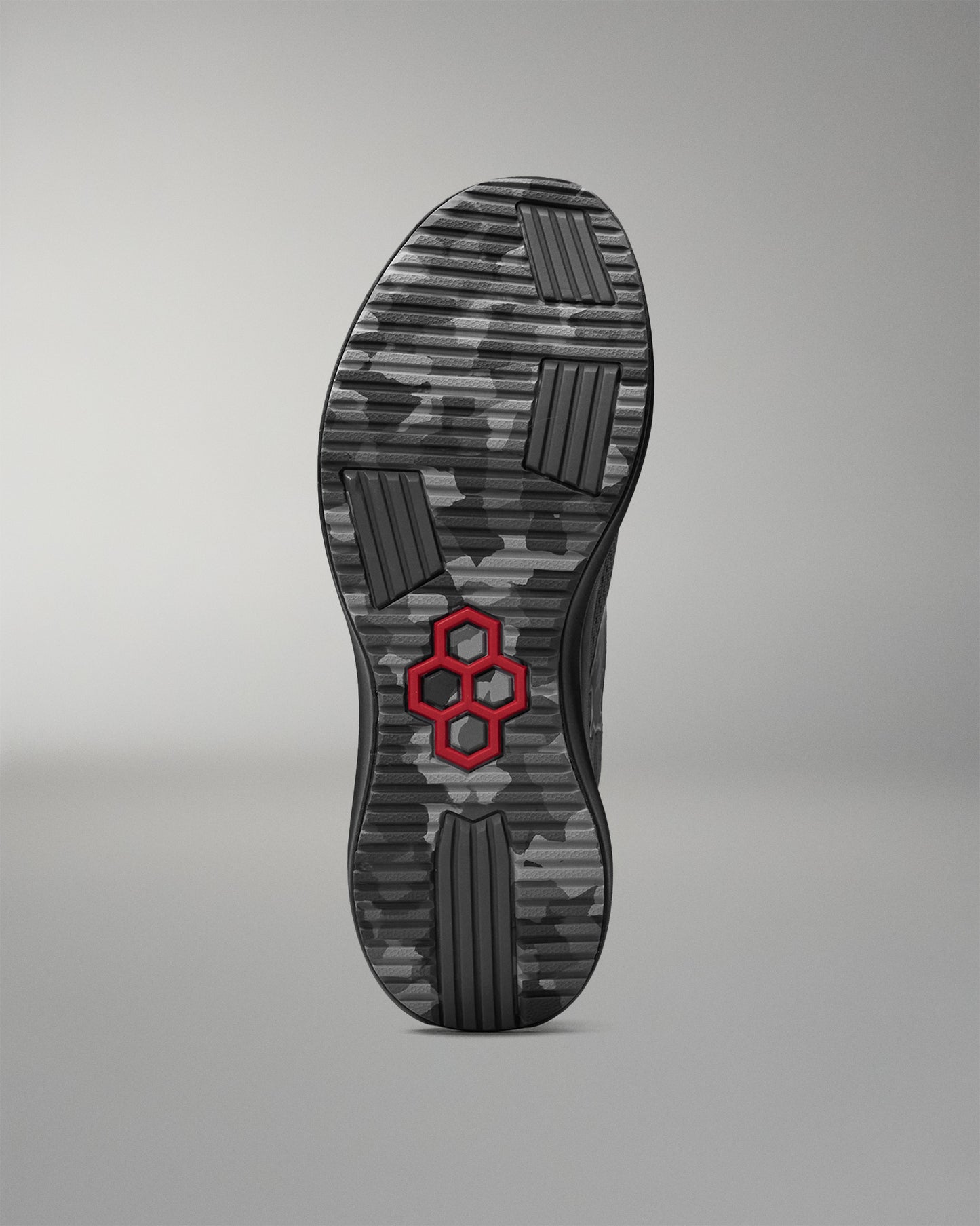 Camouflage-patterned shoe sole with a red hexagonal logo on a gray background