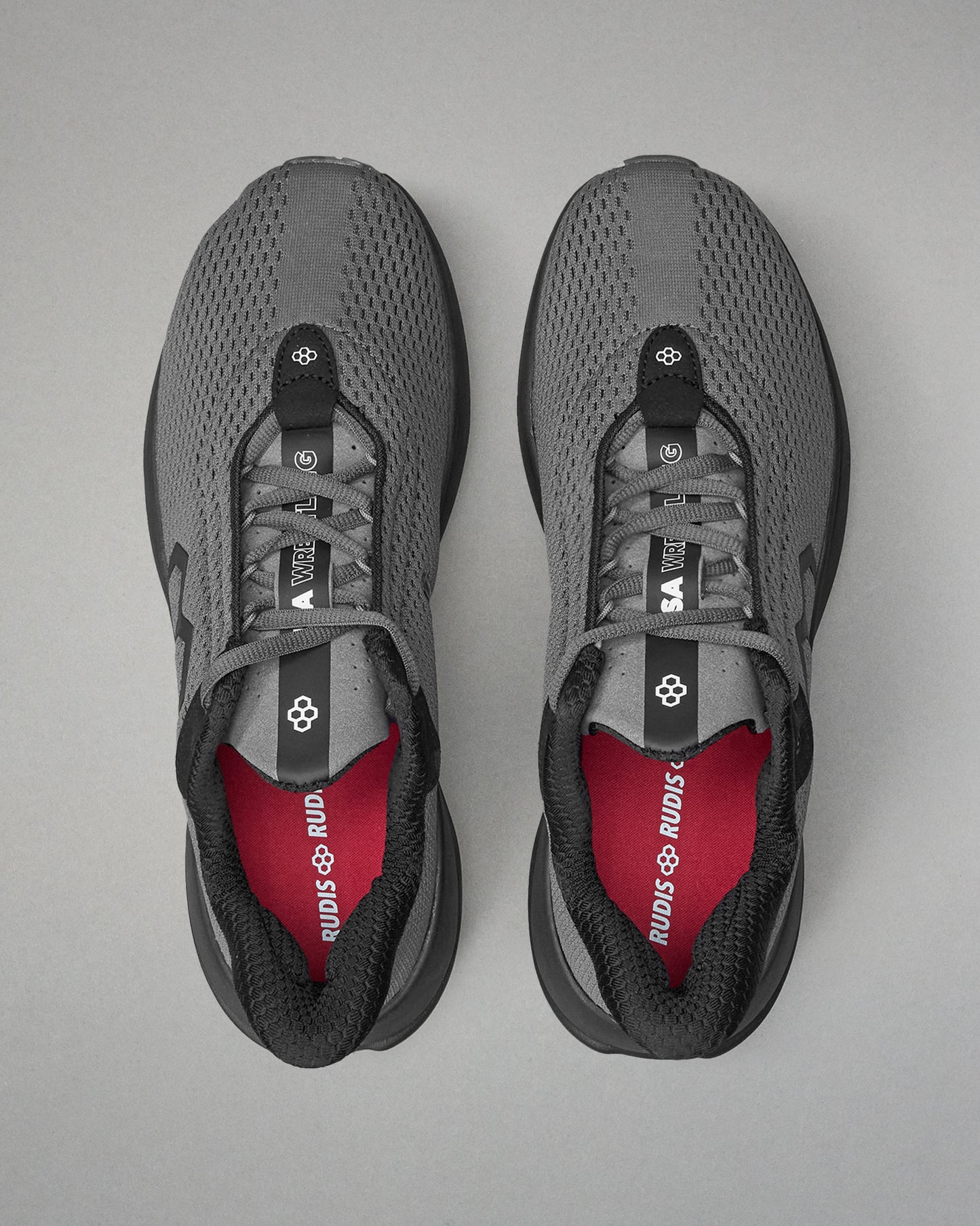 Gray athletic shoes with red lining on a gray background