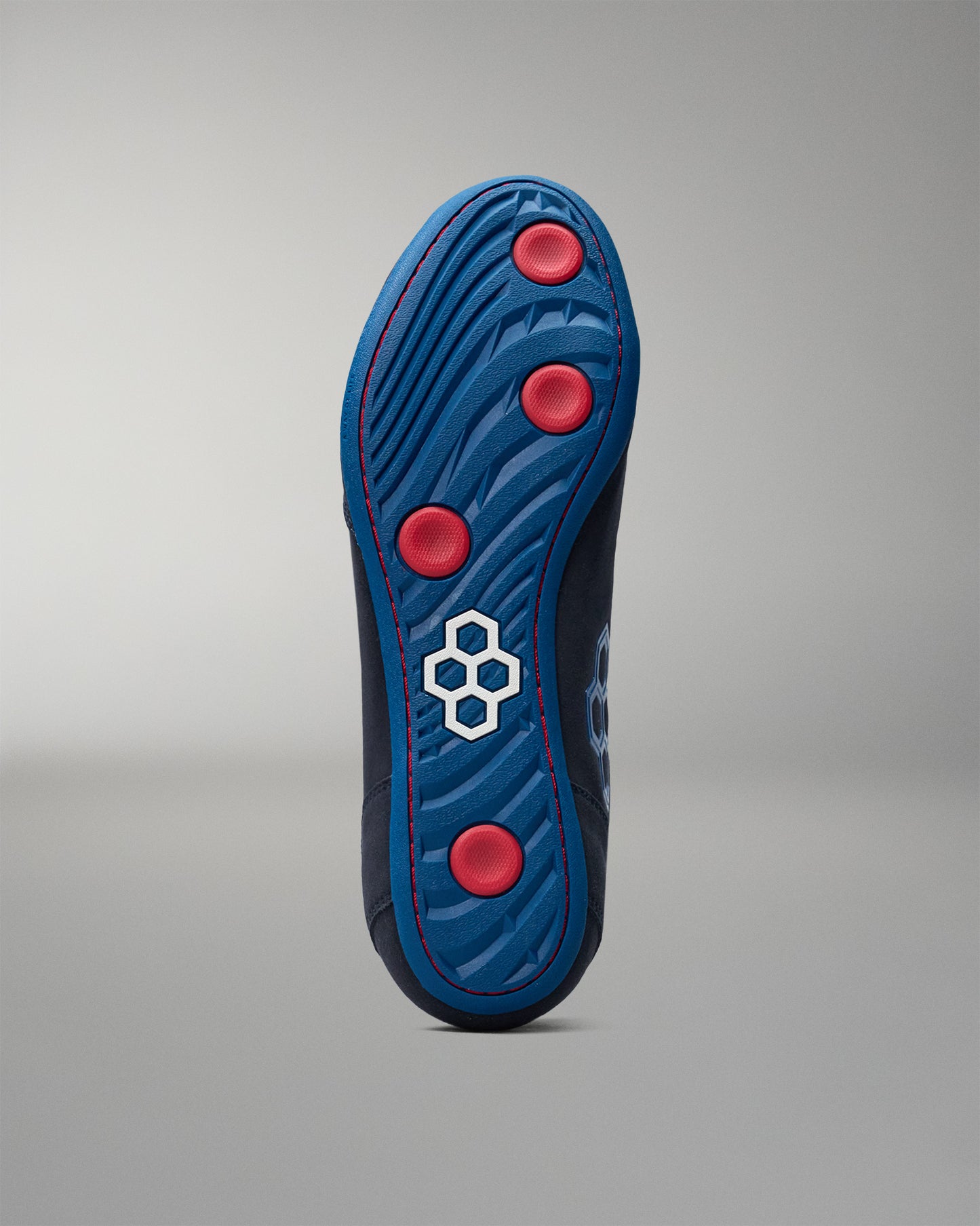 Blue wrestling shoe sole with red dots and a white logo on a gray background