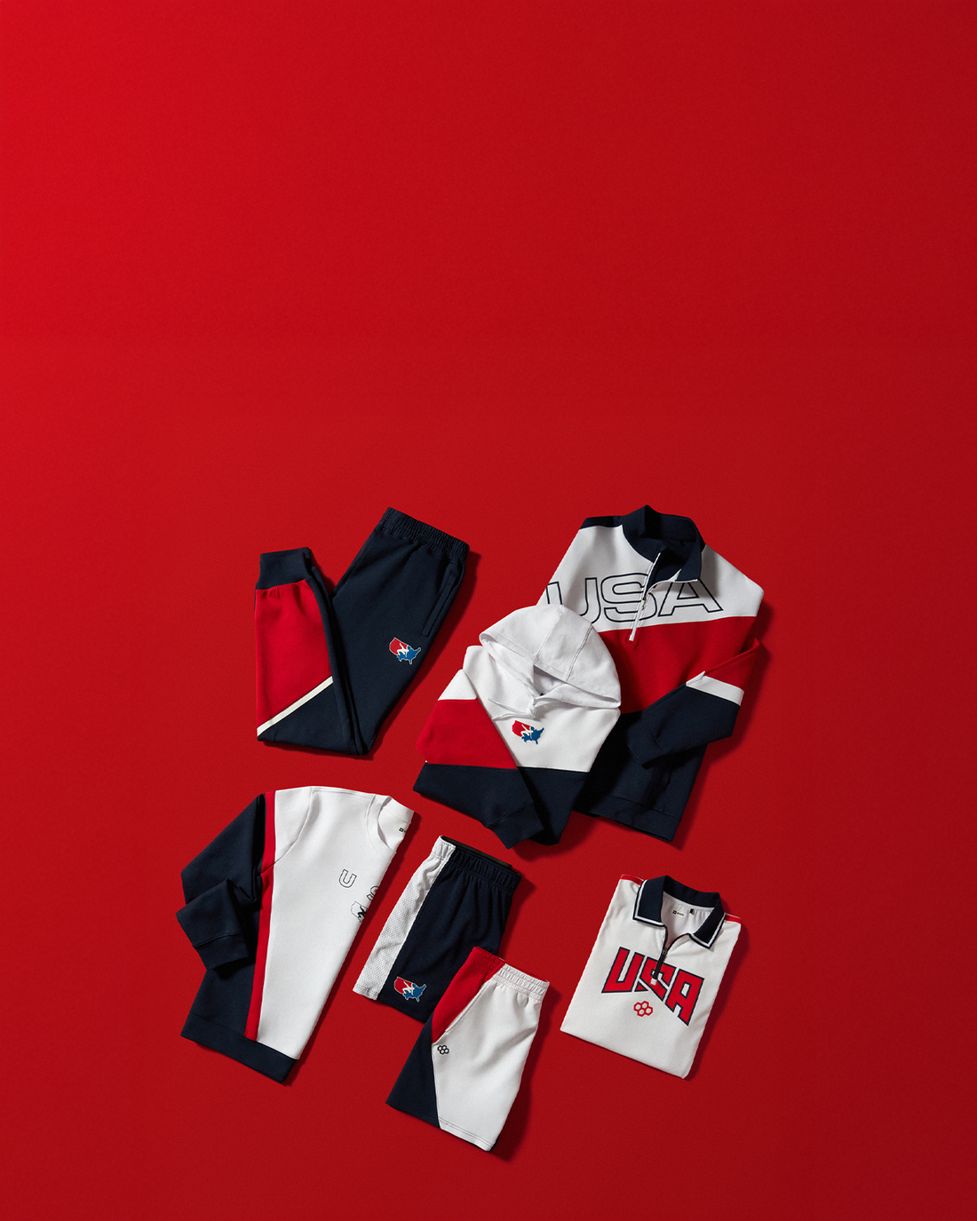 Collection of USA Wrestling clothing items including shirts and pants on a red background