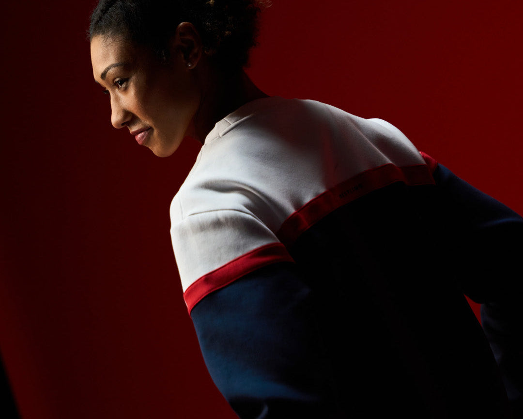 Team USA wrestler Kennedy Blades in USA Wrestling apparel by RUDIS, looking focused against a bold red backdrop – representing strength, style, and American wrestling pride.