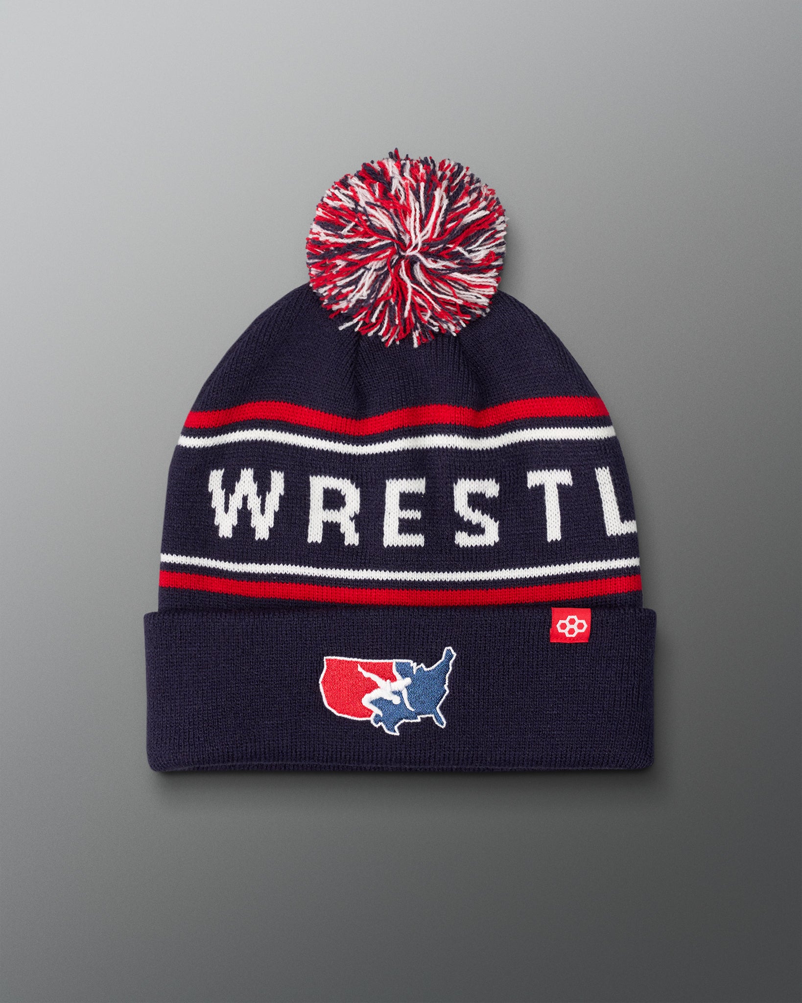 USA Wrestling Logo Navy blue beanie with red and white pom-pom on a gradient background