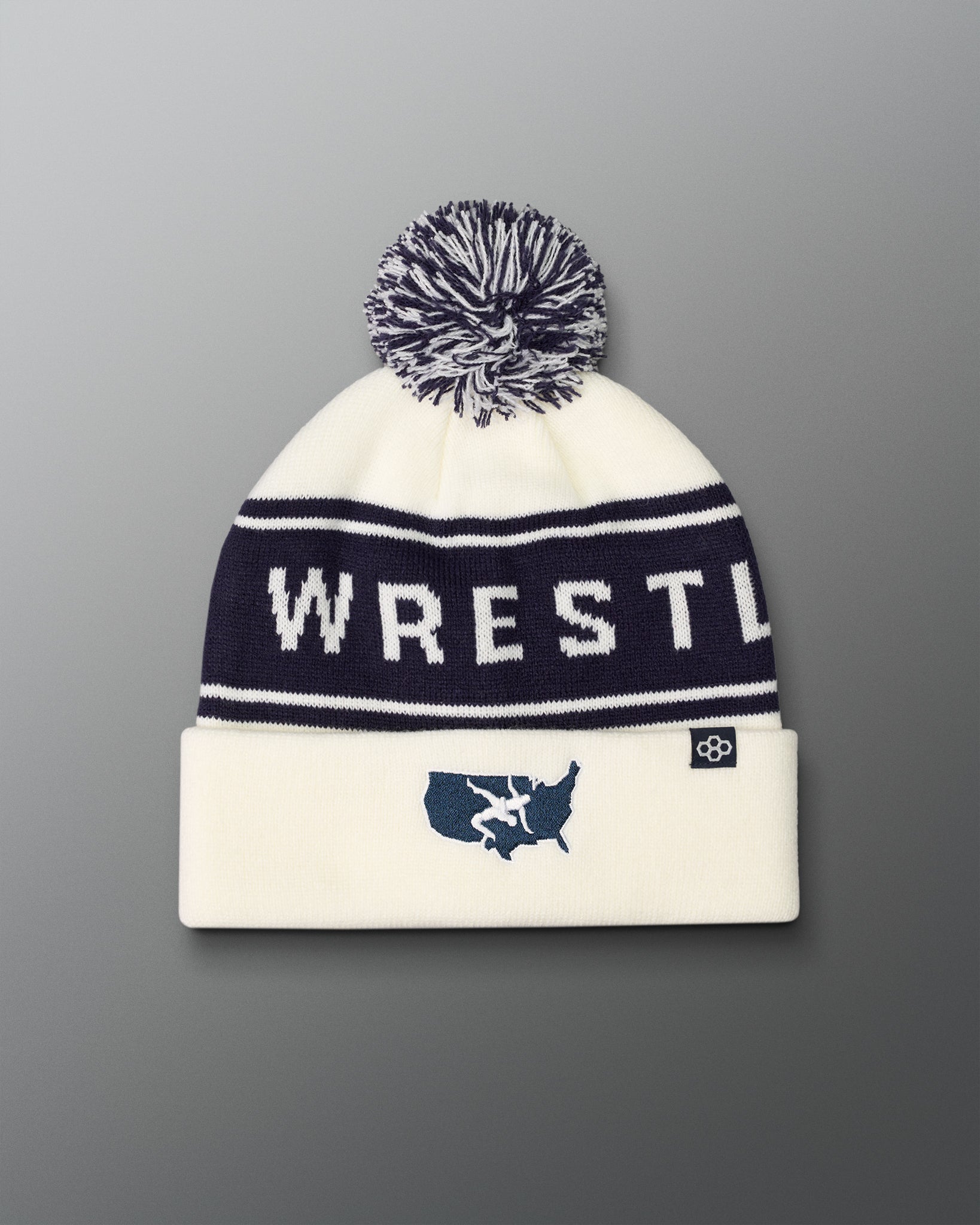 White beanie with 'WRESTLE' text and pom-pom on a gradient background with USA Wrestling logo
