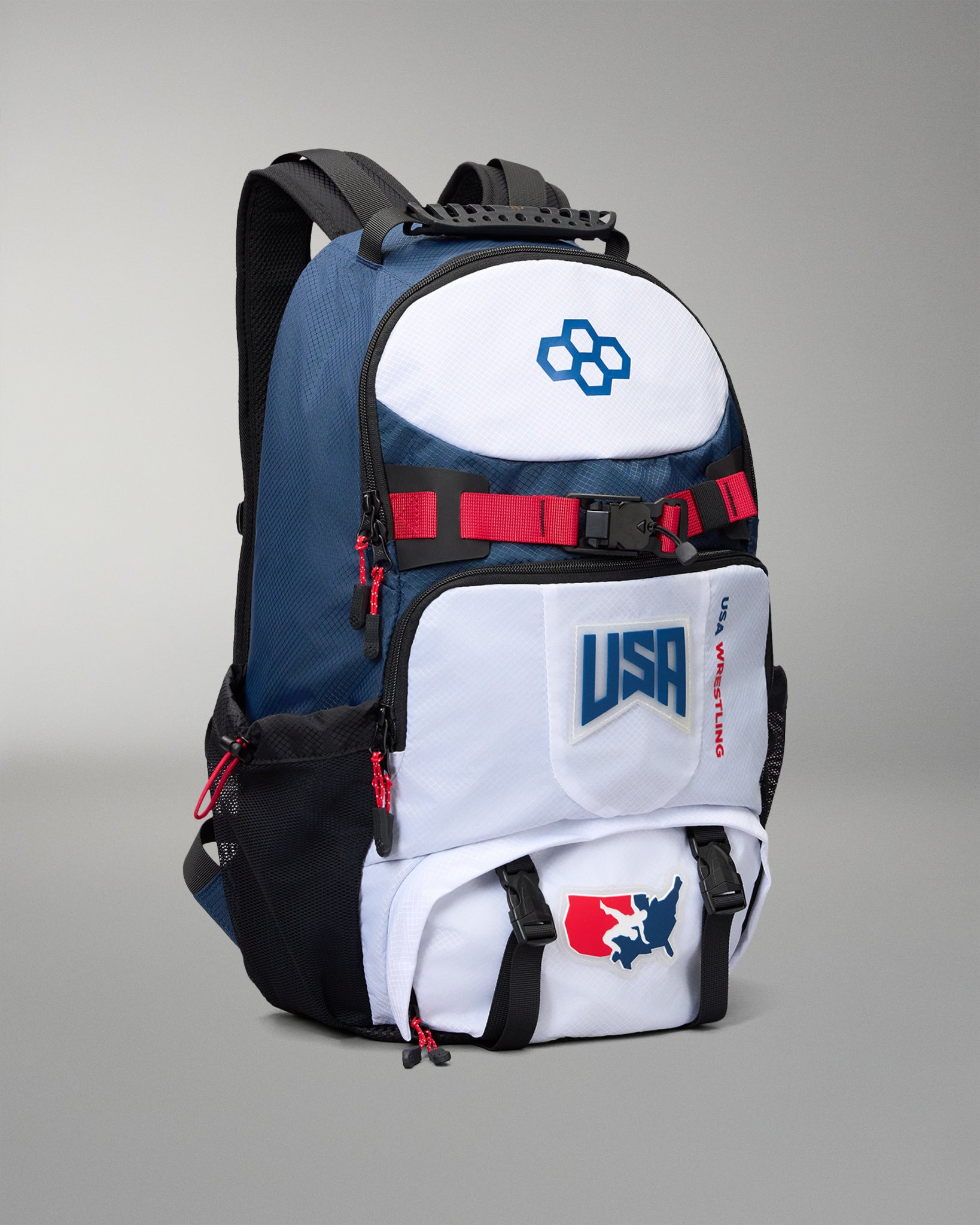 A blue, white, and black backpack with red accents, featuring USA Wrestling branding and a blue snowflake logo on a gray studio background.