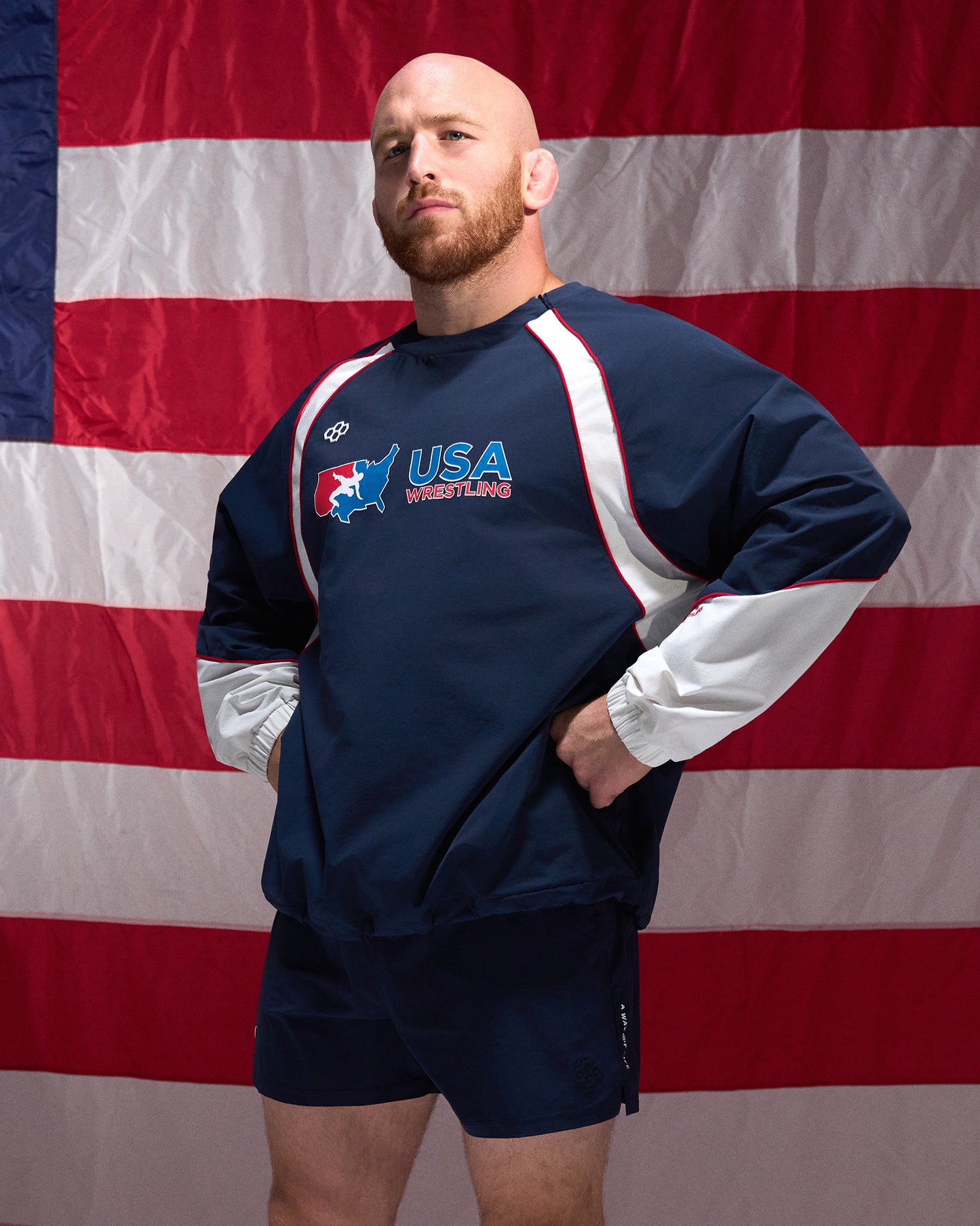 Man wearing a USA Wrestling sweatshirt in front of an American flag