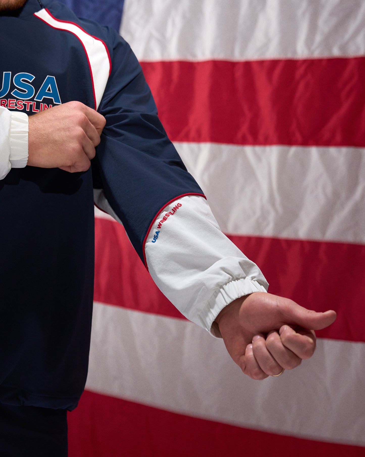 Person wearing a USA Wrestling jacket with an American flag in the background