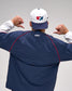 Person wearing a navy blue jacket with 'RUDIS' branding, white cap with logo, on gray background