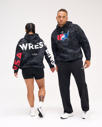 Male and female models wearing the RUDIS USA Wrestling Map Relaxed Comfort Fleece Hoodie in Black Camo, showing the USA map chest logo and bold WRESTLING back and sleeve graphics.
