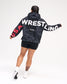 Back view of female model wearing the RUDIS USA Wrestling Map fleece hoodie in Black Camo, featuring oversized white WRESTLING lettering and red USA sleeve graphics.