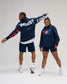 Male and female models wearing the RUDIS USA Wrestling Map Relaxed Comfort Fleece Hoodie in Navy, showcasing the patriotic chest logo and bold USA WRESTLING sleeve and back graphics.